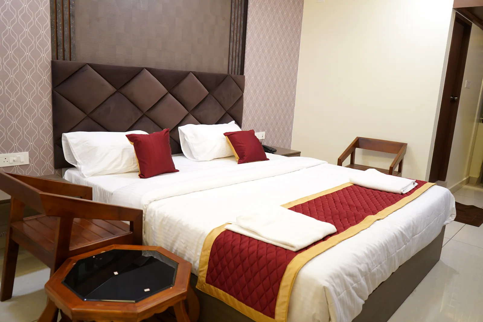 Deluxe room with a king bed, upholstered headboard and wooden armchairs